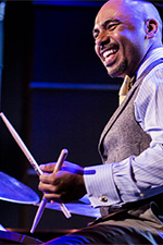 Professional drummer Ali Jackson playing drum set in concert.