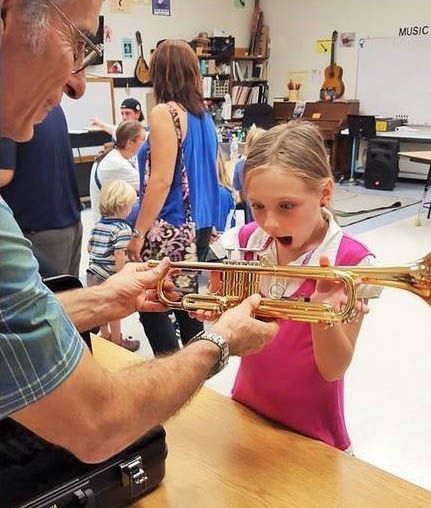 Girl in a pink shirt is very excited to receive her first trumpet.